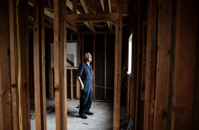 Roy stands in the back of his home.